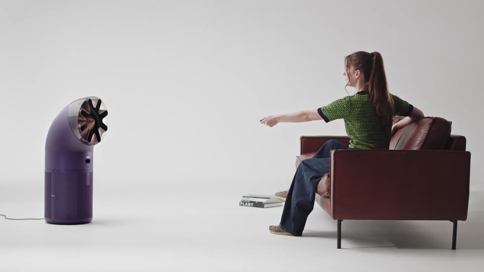 A woman on a sofa pointing the remote at the HushJet Big+Quiet