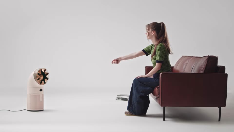 A woman on a sofa pointing the remote at the HushJet Hot Cool Pure+